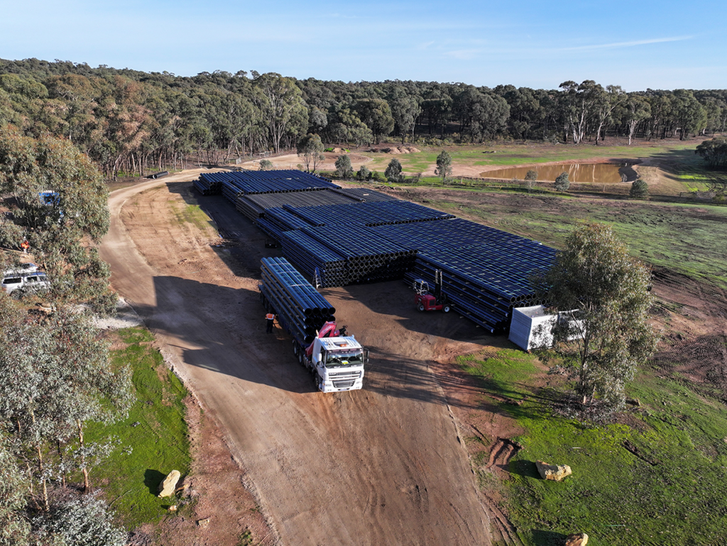 Aerial view of truck departing site storage location with a full load of pipe