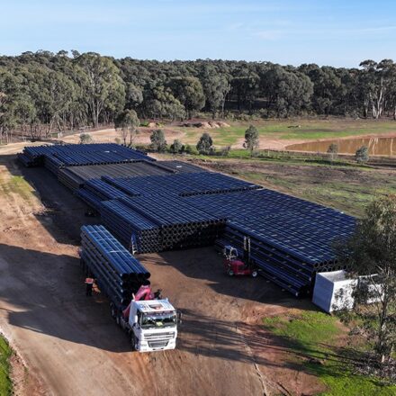 Aerial view of truck departing site storage location with a full load of pipe