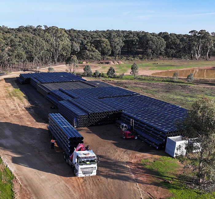 Aerial view of truck departing site storage location with a full load of pipe